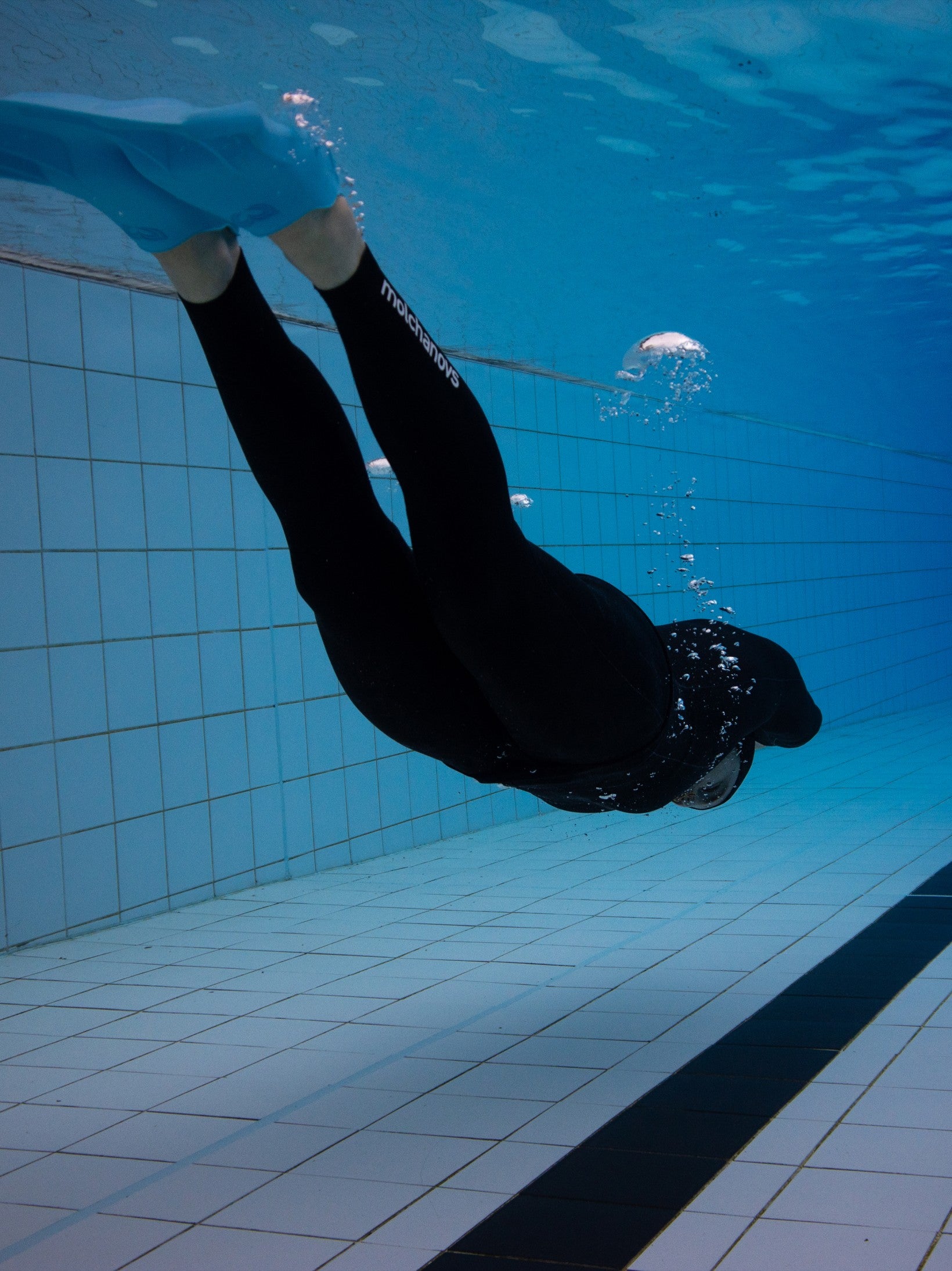 A freediver doing DYN wearing a black smoothskin wetsuit.