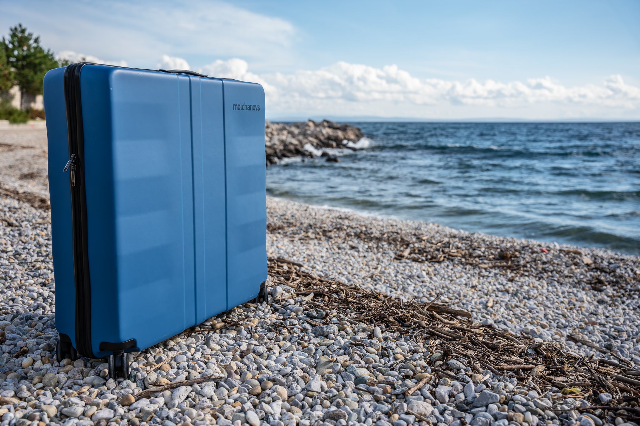 Blue Hard Case on a beach with pebbled floor and waves in the background